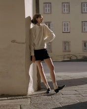 Load image into Gallery viewer, A model leaning on the wall in the sun in white sweater and black skirt wearing Yuni Buffa Fez Penny Loafer shoe in Navy blue color made in Italy with Italian Lamb Nappa leather