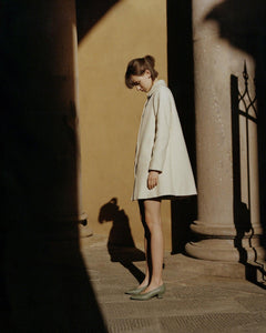 A model standing in the sun in a Tuscan town wearing Yuni Buffa Roma Pump shoe in Sage green color made in Italy with soft quilted Italian Lamb Nappa leather