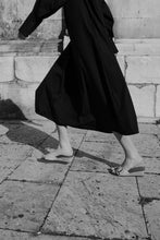 Load image into Gallery viewer, A model dressed in long navy shirt dress running in a sunny Tuscan piazza wearing Yuni Buffa Lucca Sardinian cork wedge sandal shoe in Sage green color with tan vachetta leather insole and crepe rubber outsole made in Italy with Italian Lamb Nappa leather