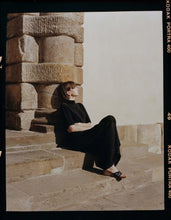 Load image into Gallery viewer, A model dressed in black sitting on  sunny Tuscan steps wearing Yuni Buffa Lucca Sardinian cork wedge sandal shoe in Navy blue color with tan vachetta leather insole and crepe rubber outsole made in Italy with Italian Lamb Nappa leather