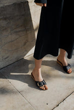 Load image into Gallery viewer, A model in a navy long shirt dress standing in a sunny Tuscan piazza wearing Yuni Buffa Lucca Sardinian cork wedge sandal shoe in Navy blue color with tan vachetta leather insole and crepe rubber outsole made in Italy with Italian Lamb Nappa leather
